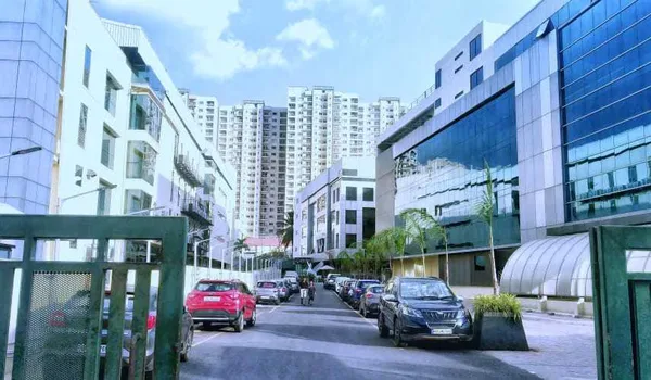AKR Tech Park, Bangalore — office blocks either side of the internal access road, with parked cars and the gate in the foreground