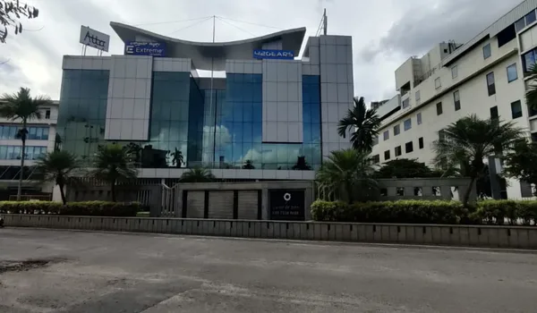 AMR Tech Park, Bangalore — glass-fronted office building with tenant signage across the upper floors and palms along the road frontage
