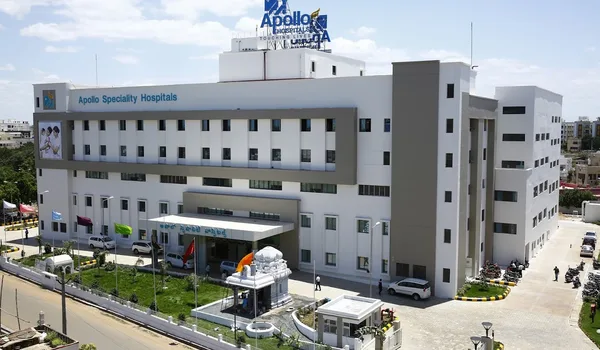 Apollo Hospitals, Bangalore — white hospital block with the Apollo Speciality Hospitals lettering on the facade, a rooftop Apollo Hospitals sign and the entrance porch below