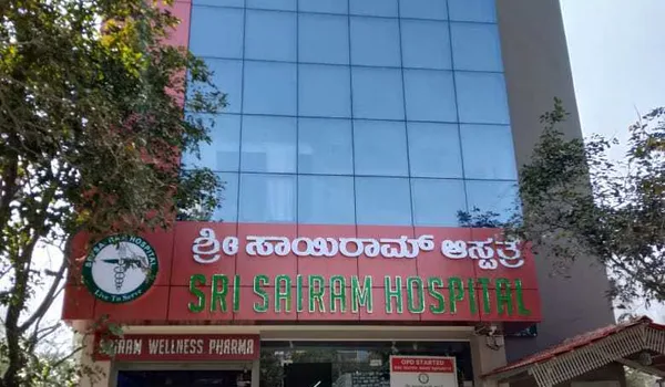 Sri Sairam Hospital, Hulimavu, Bangalore — red signboard carrying the hospital name in Kannada and English above the entrance and the pharmacy below