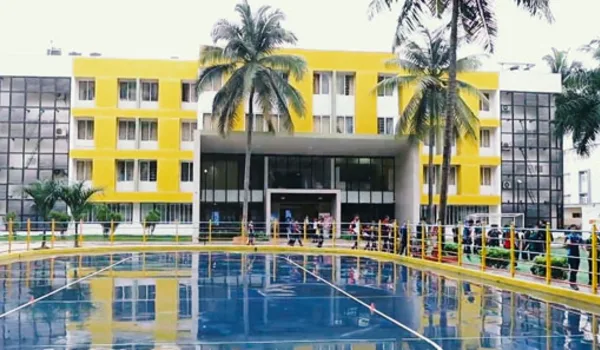 VIBGYOR High School Bannerghatta, Bangalore — yellow and grey four-storey school block behind the campus swimming pool